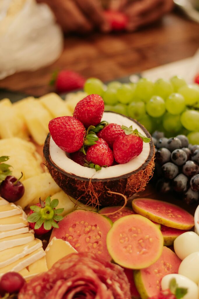 A vibrant tropical fruit platter featuring strawberries in a coconut shell among an array of fruits.